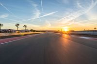 a photo of a dirt race track with sun setting in the distance of the track