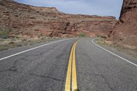 a person riding a motorcycle along a narrow road through rocks and sand cliffs a grassy area on both sides