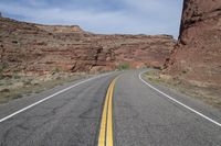 a person riding a motorcycle along a narrow road through rocks and sand cliffs a grassy area on both sides