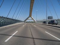 a truck driving across a bridge near a street corner near buildings and a bridge with many cables