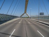 a truck driving across a bridge near a street corner near buildings and a bridge with many cables