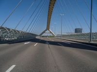 a truck driving across a bridge near a street corner near buildings and a bridge with many cables