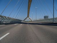 a truck driving across a bridge near a street corner near buildings and a bridge with many cables