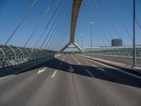 a truck driving across a bridge near a street corner near buildings and a bridge with many cables