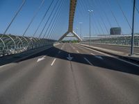 a truck driving across a bridge near a street corner near buildings and a bridge with many cables