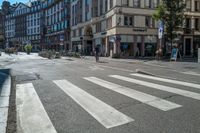 a crosswalk at the intersection in a european city with parked bikes in it is very empty