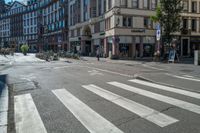 a crosswalk at the intersection in a european city with parked bikes in it is very empty