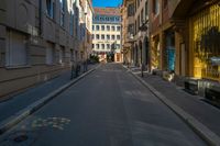 a view of a quiet street through a narrow alleyway with buildings in the background