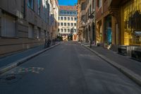 a view of a quiet street through a narrow alleyway with buildings in the background