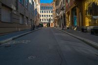 a view of a quiet street through a narrow alleyway with buildings in the background