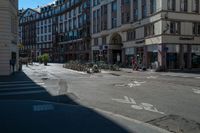 a city street with a building and multiple buildings in the background is blue sky with sun shining down