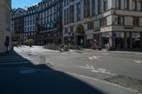 a city street with a building and multiple buildings in the background is blue sky with sun shining down