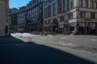 a city street with a building and multiple buildings in the background is blue sky with sun shining down