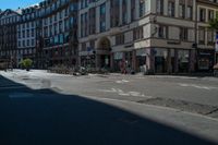 a city street with a building and multiple buildings in the background is blue sky with sun shining down