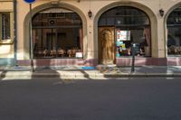 there is a woman walking down the street with a black bag in her hand and the sidewalk of front of the store