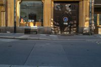 a brown door on the side of an apartment building next to a street with a bench in front