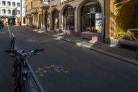 a bike that is leaning on a gate near the street and buildings that have been painted with orange, yellow, white and blue marker markers