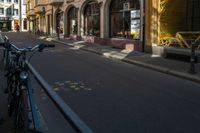 a bike that is leaning on a gate near the street and buildings that have been painted with orange, yellow, white and blue marker markers