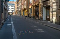 an empty city street with buildings on either side and colored dots painted on the street