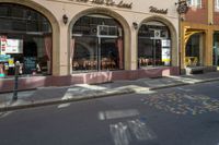 a restaurant with a sign and many windows in the foreground and colorful lettering painted on the street