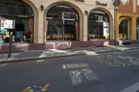 a restaurant with a sign and many windows in the foreground and colorful lettering painted on the street