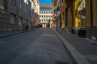 there is a narrow street with buildings in the background and bicycle racks on the curb