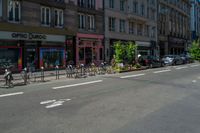 bicycles are parked in the corner by the curb and buildings on the other side of the road