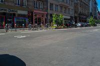 bicycles are parked in the corner by the curb and buildings on the other side of the road