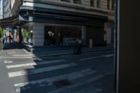 a group of people standing on a sidewalk waiting to cross the street under a crosswalk