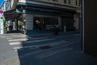 a group of people standing on a sidewalk waiting to cross the street under a crosswalk