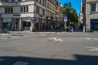 the man is crossing the crosswalk in front of some buildings, with bikes and bicycles on either side