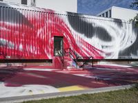 an empty bench and some graffiti on the outside of a building's wall in red, white and blue