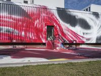 an empty bench and some graffiti on the outside of a building's wall in red, white and blue