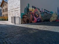 street view with brick buildings and an outdoor bench near wall, in large area with colorful street art