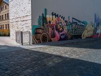 street view with brick buildings and an outdoor bench near wall, in large area with colorful street art