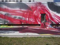 a man walking near a red painted wall with graffiti on it's walls and stairs