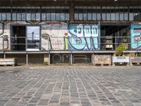 an old factory with graffiti and a sign with the word'still shut'in blue