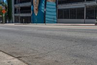 a man wearing a wet suit crossing an intersection with his skateboard on the sidewalk