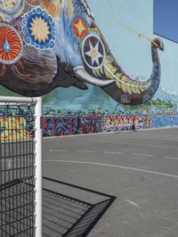 this is an outdoor public space with a mural of an elephant on the side of a building