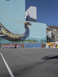 this is an outdoor public space with a mural of an elephant on the side of a building