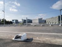 an image of a broken microwave lying in the street by some buildings near an empty road