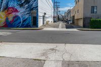 a colorful mural on the side of a building on the corner is an empty street