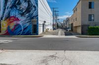 a colorful mural on the side of a building on the corner is an empty street