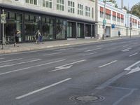 a street in a city has a bicycle lane and several pedestrians on it is in the distance