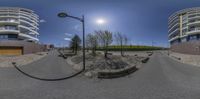 a view from 360 - angle of the street next to buildings, with a sun, trees and rocks near by