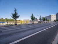 a picture of a city street and some buildings in the background of this photo and trees near an asphalt roadway