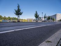 a picture of a city street and some buildings in the background of this photo and trees near an asphalt roadway