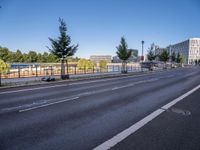 a picture of a city street and some buildings in the background of this photo and trees near an asphalt roadway