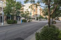 a empty street in the city with buildings and trees lined up on either side of the road