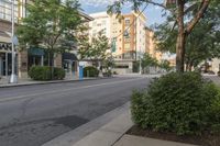 a empty street in the city with buildings and trees lined up on either side of the road